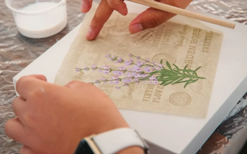 Dłonie przyklejają papierowy motyw do drewnianej skrzynki